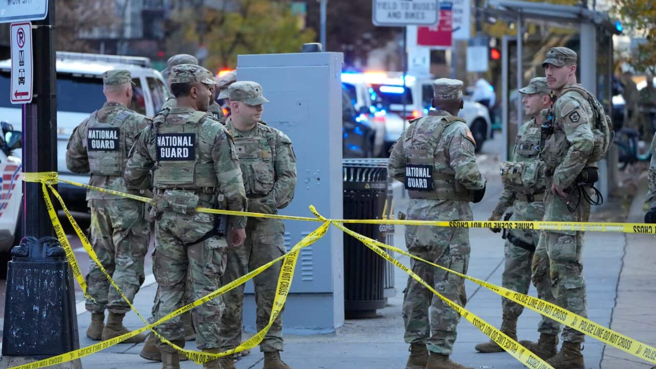 National guard members in camoflague standing near crime scene tape.