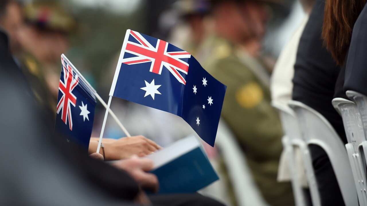 Memmbers of the public hold flags at an Australia Day Citizenship Ceremony and Flag Raising event in Canberra.