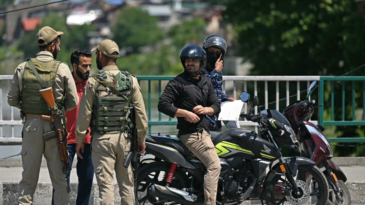 Two policemen inspect commuters on bikes