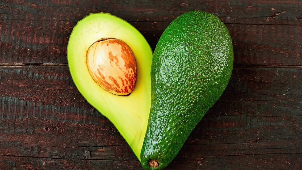 Fresh avocado in the shape of a heart isolated on wood table background. Love symbol made of fruit. Exotic fruit.