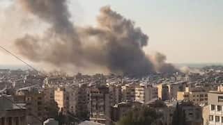 A cloud of smoke rising from above buildings.