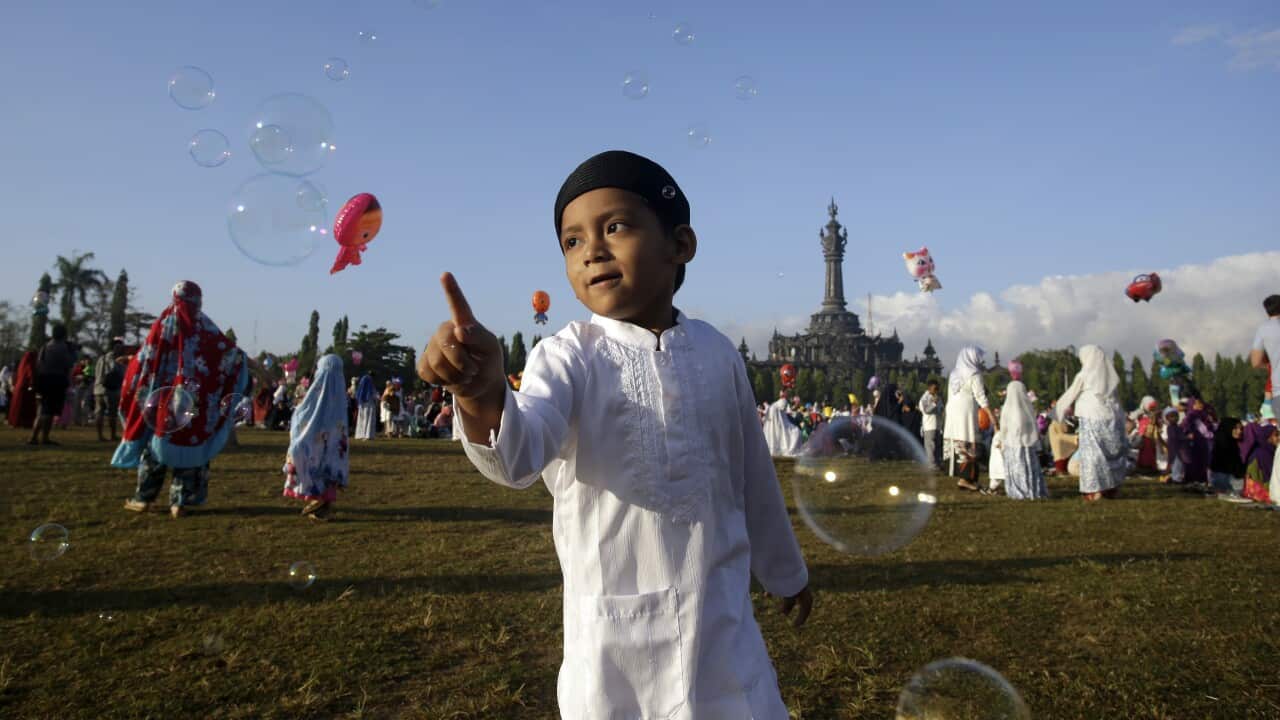 A muslim boy plays with bubble as he attend an Eid al-Fitr prayer to mark the end of the holy fasting month of Ramadan in Bali, Indonesia.