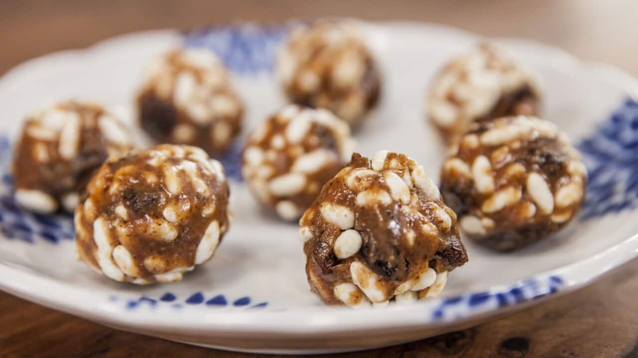 Eight energy balls sit on a patterned blue plate.