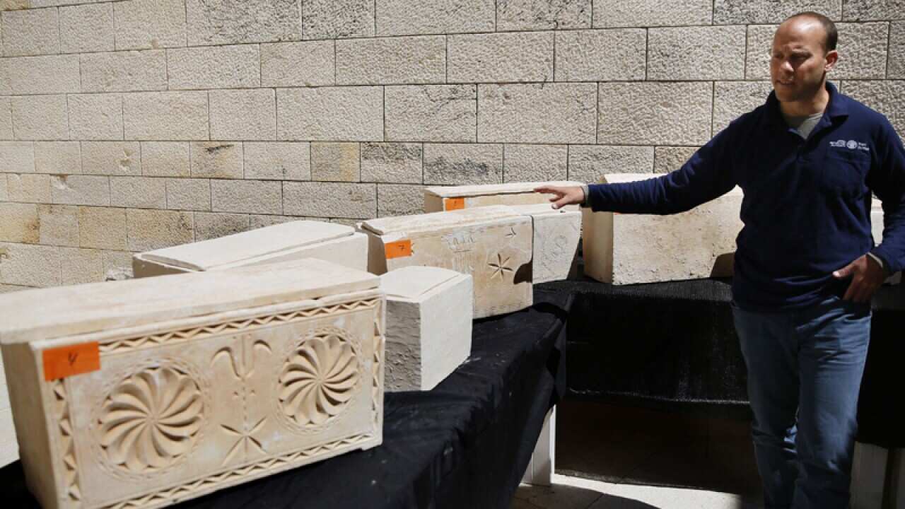 An archaeologist with one of 11 ancient Jewish burial caskets
