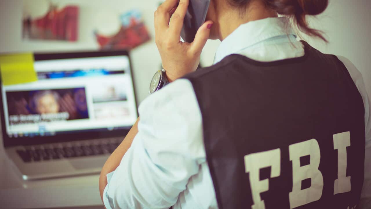 FBI woman in office talking on phone.