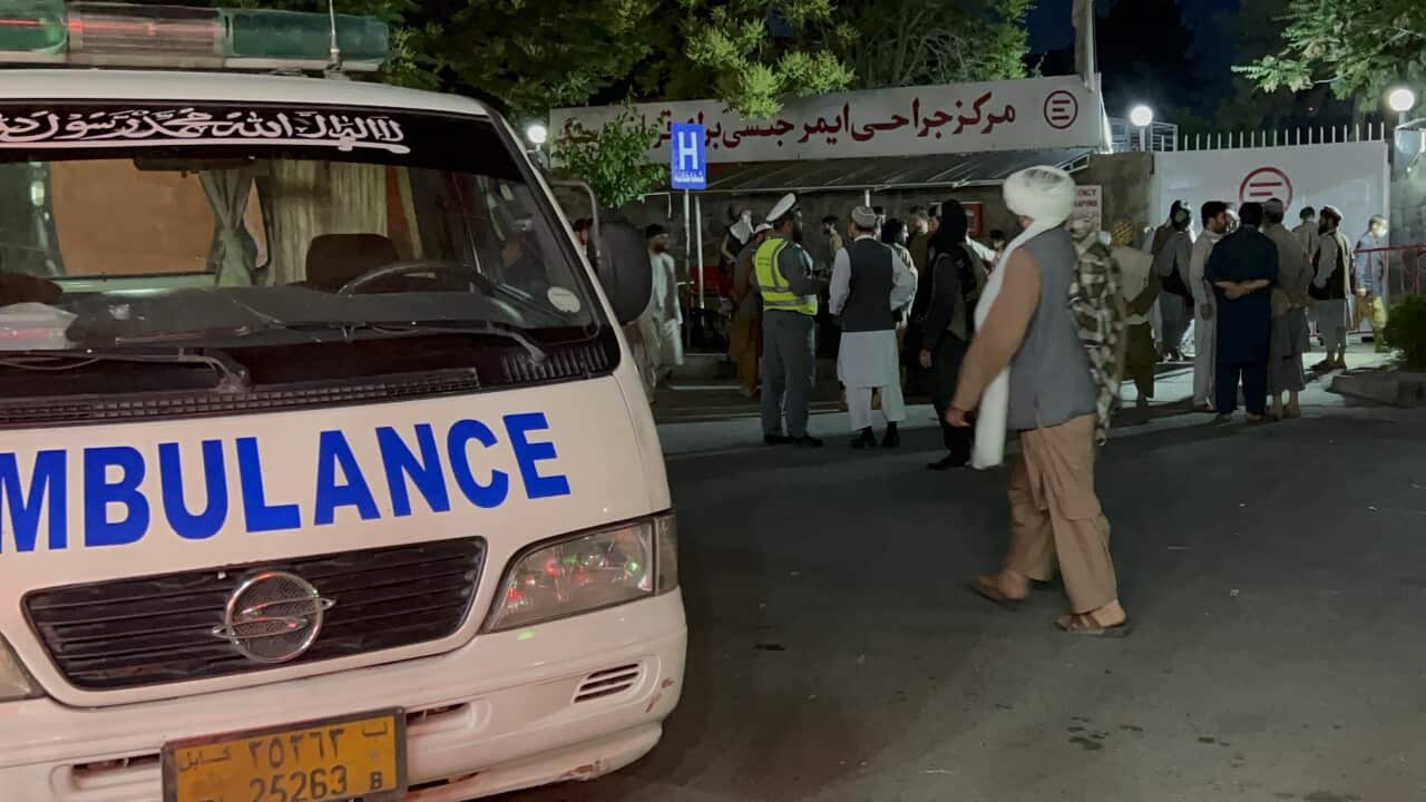 A crowd of people standing near an ambulance.