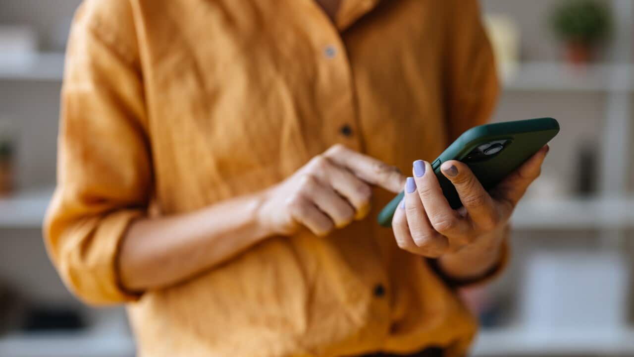 An Unrecognizable Businesswoman Using Her Mobile Phone While Working In The Office