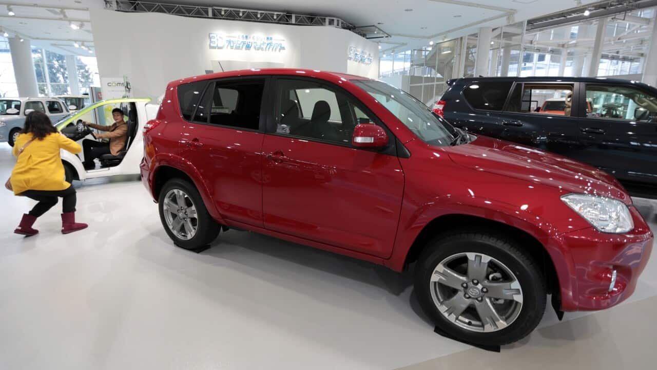 A woman takes a photograph of her partner sitting inside a vehicle at Toyota's showroom in Tokyo. Toyota is expected to report Tuesday that net income quadrupled to 434.3 billion yen ($4.3 billion) last quarter. (Yuriko Nakao)