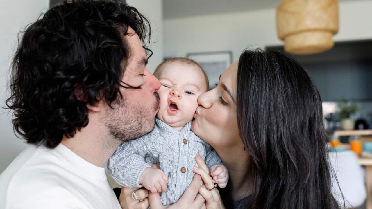 Father and mother kissing baby boy at home