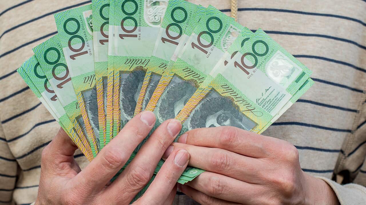 A person holding Australian $100 banknotes