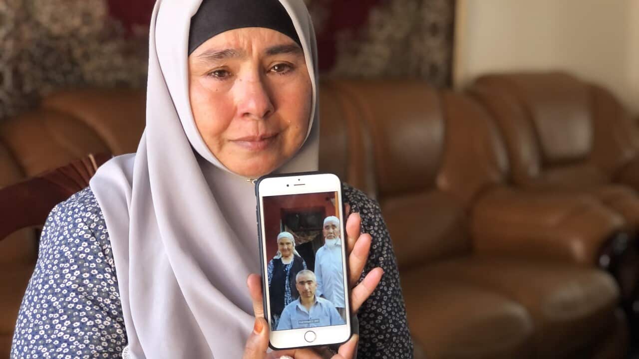 Horigul Yusuf holds a photo of her younger brother, now detained, her mother and her father, whose death she learnt about a month after he died