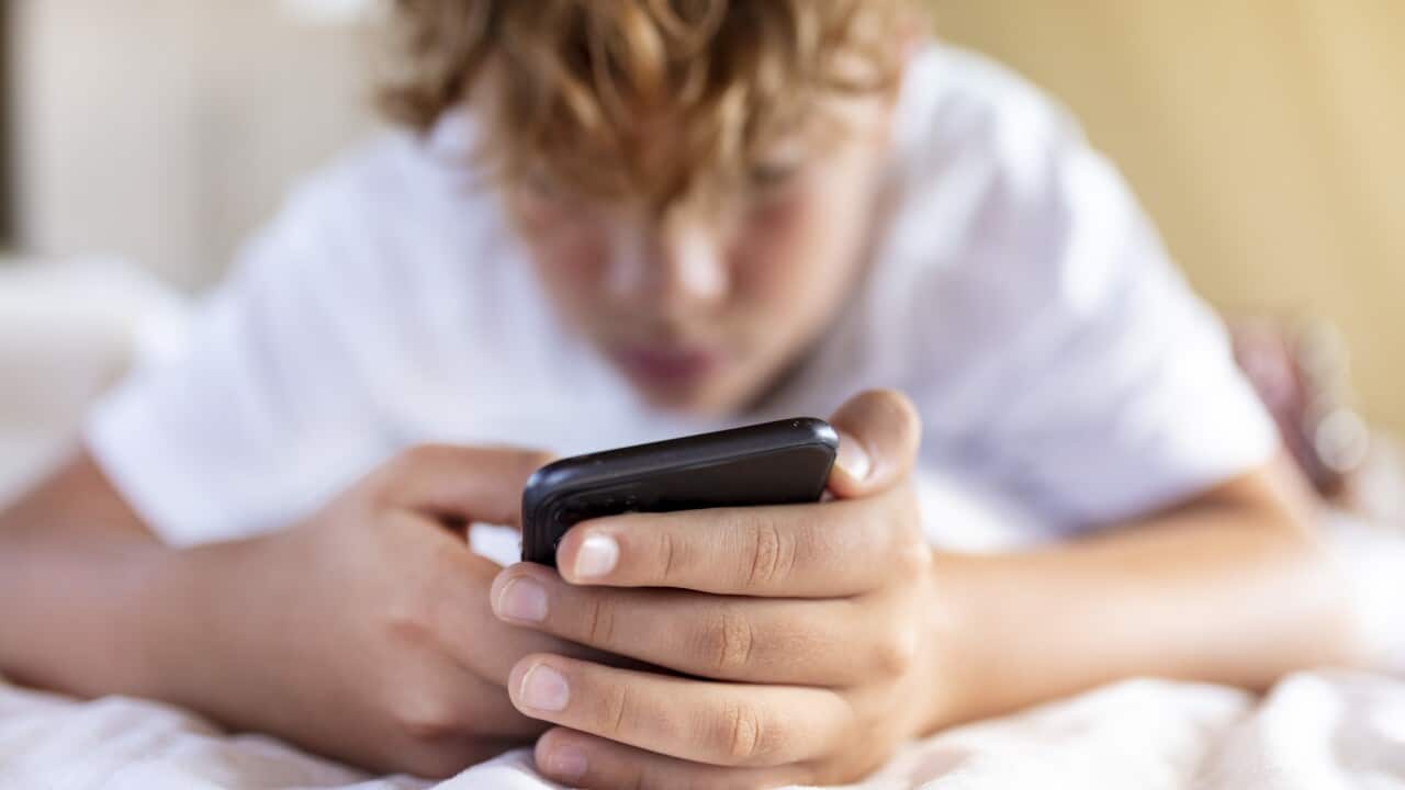 A close up shot of a teen boy holding his phone with two hands