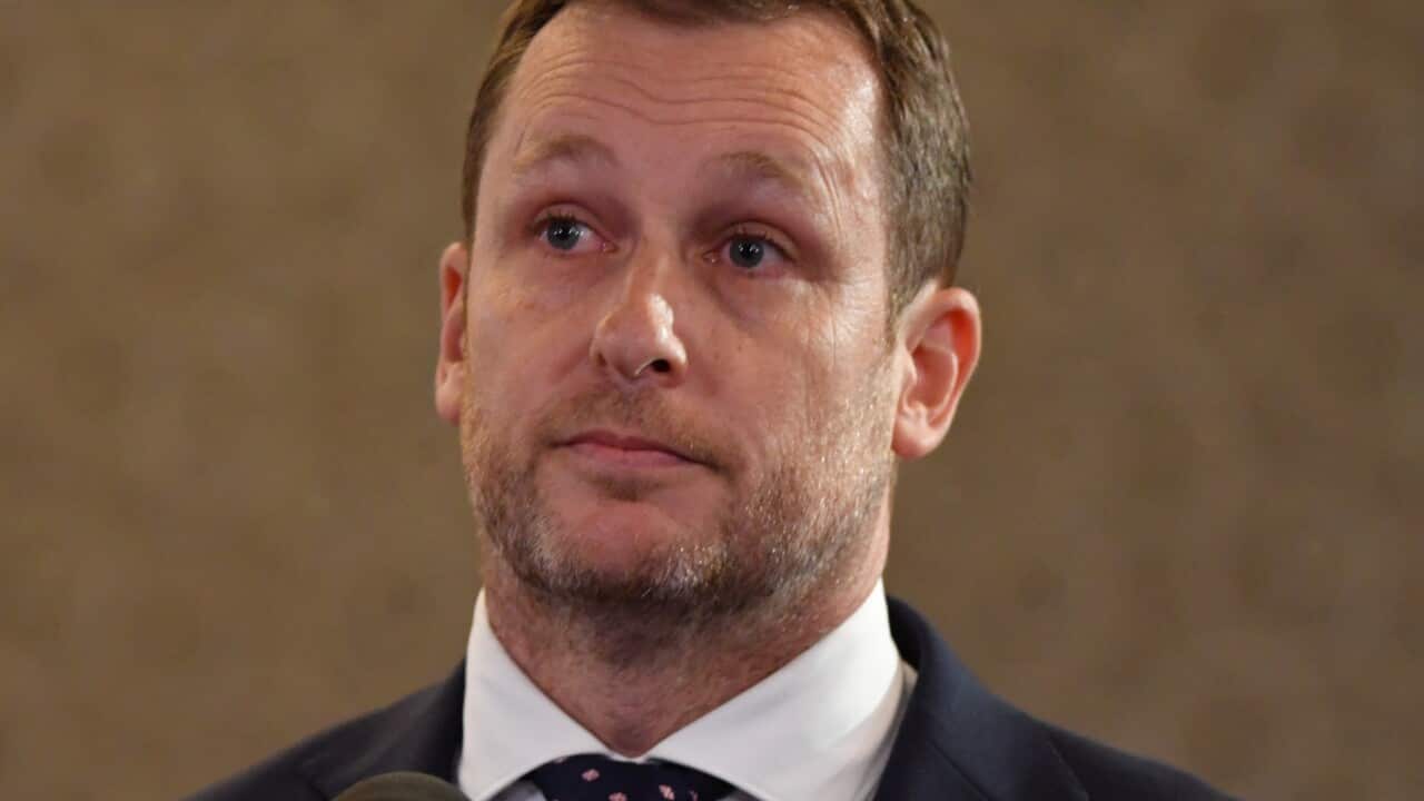 Peter van Onselen wearing a suit and standing in front of a microphone.