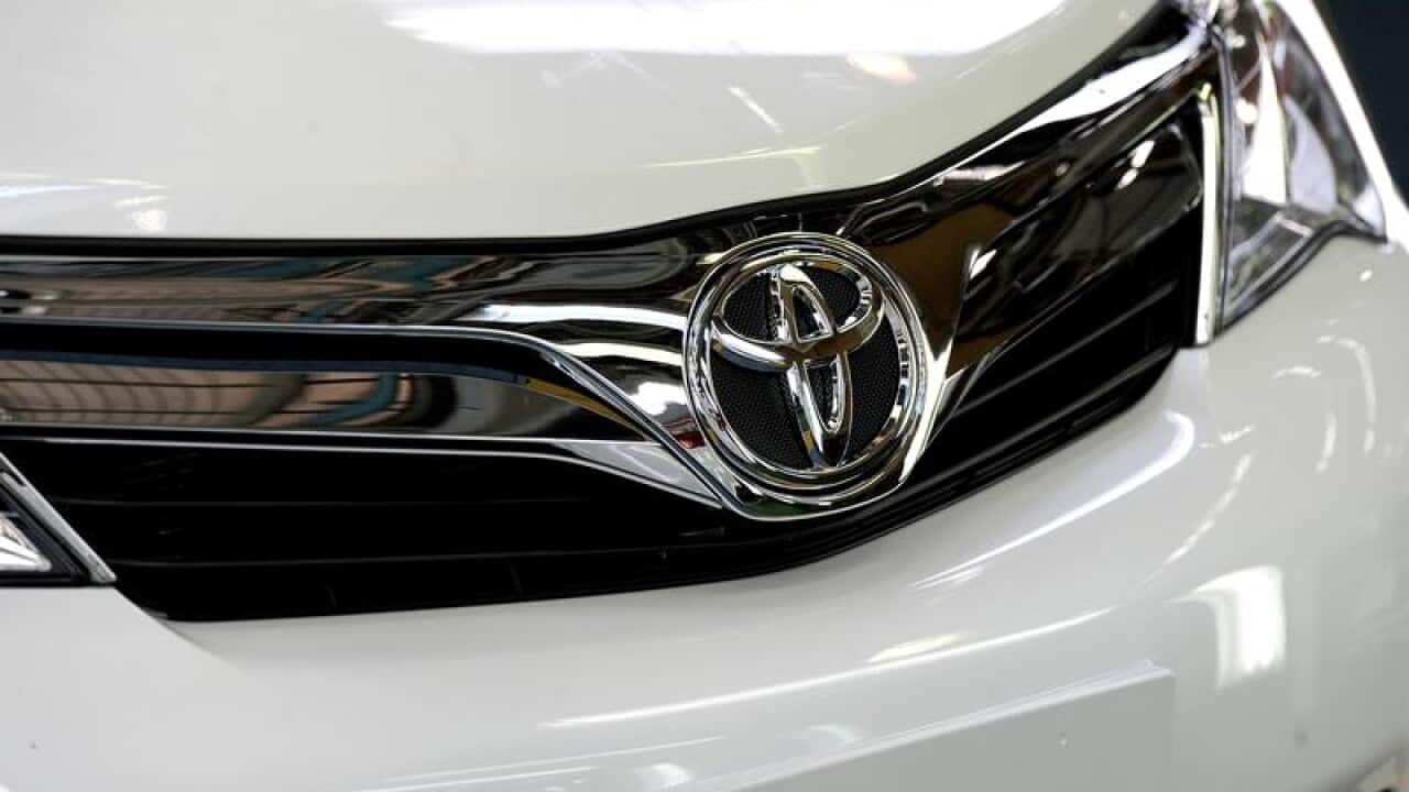 The front of a Toyota car is seen in a factory.
