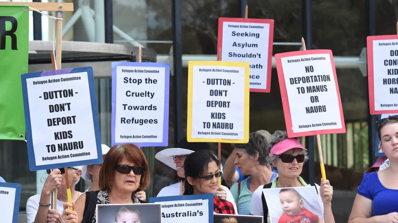 Asylum seeker advocates hold signs after the High Court decision.