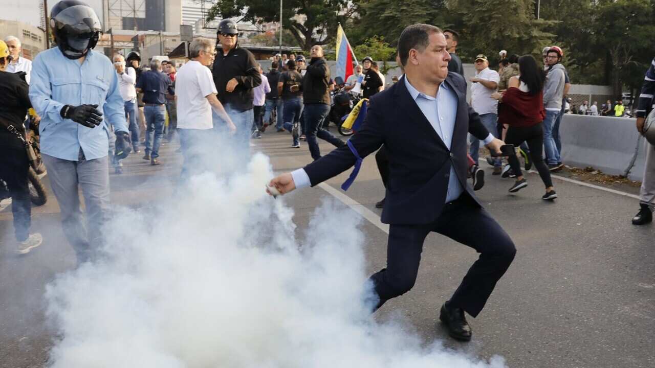 An opponent to Venezuela's President Nicolas Maduro returns a tear gas canister in Caracas.