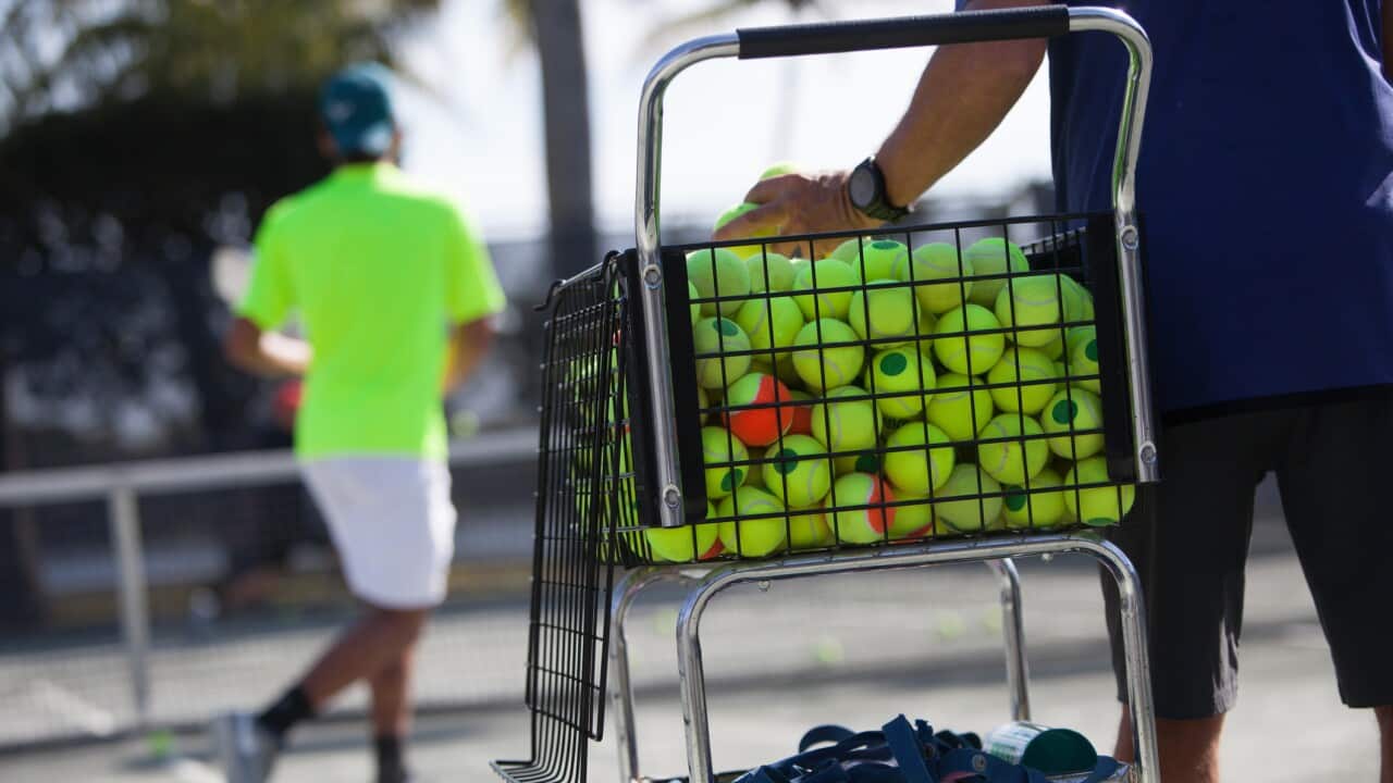 Tennis coach training teenage boys in court