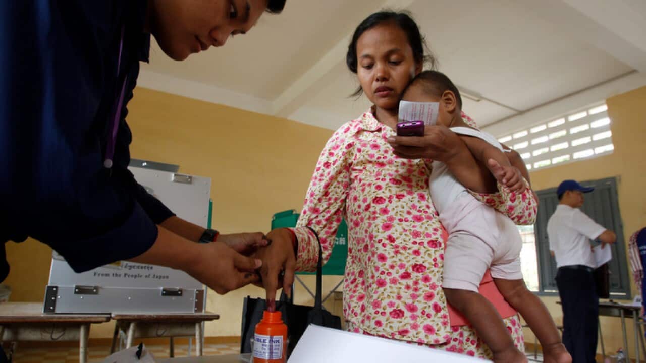 A villager has her finger inked after voting in Cambodia's election