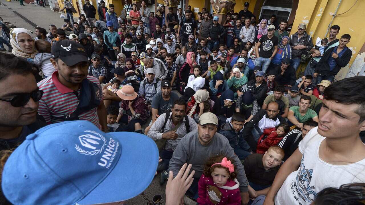 A UNICEF worker talks to a group of the migrants waiting at the train station in the southern city of Gevgelija. (EPA)