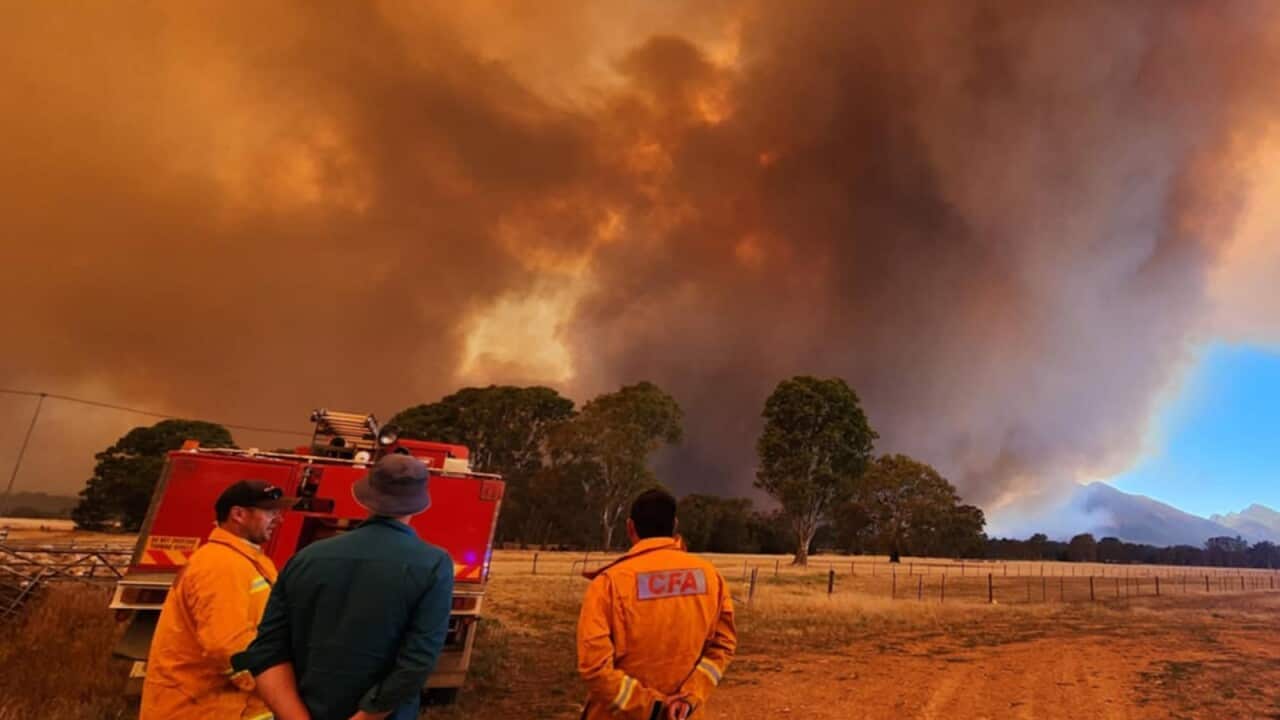 An out of control bushfire as firefighters watch on.