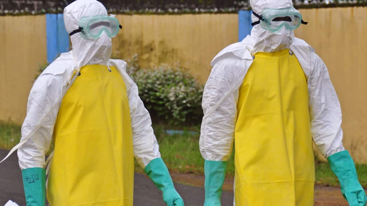 Health workers wear protective gear to remove a body