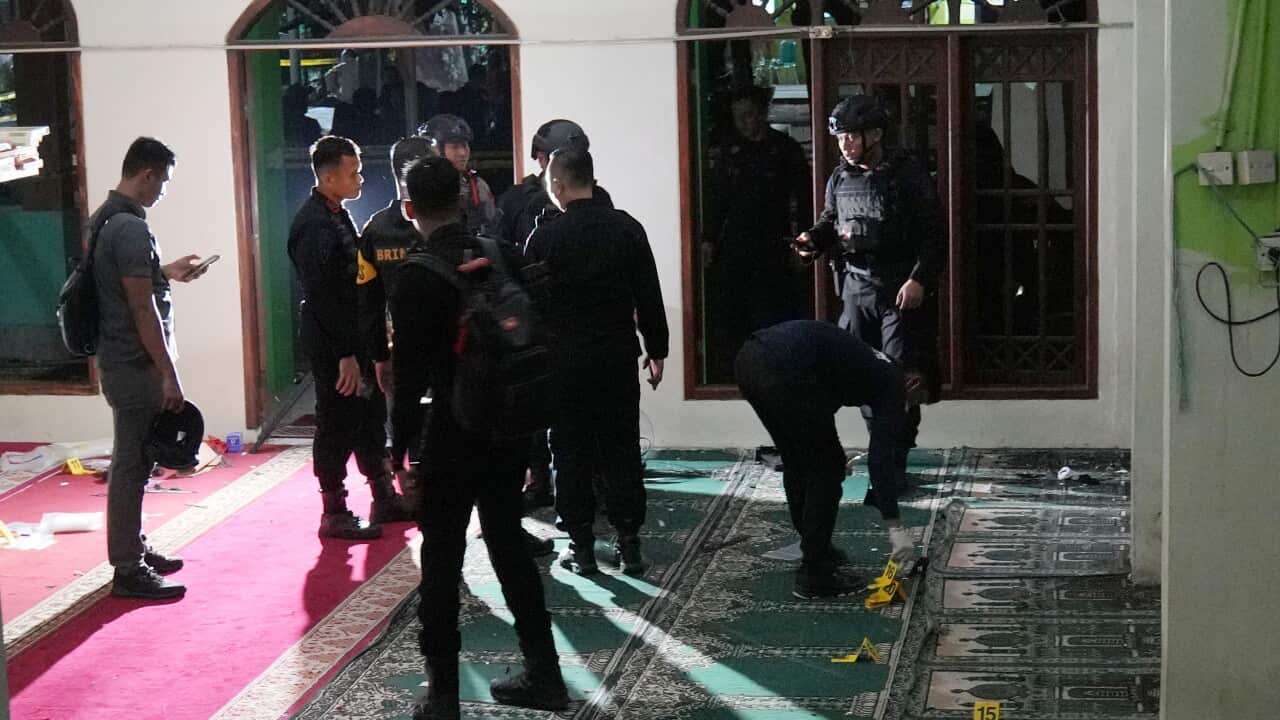 A group of men in black uniforms stand inside a building at night