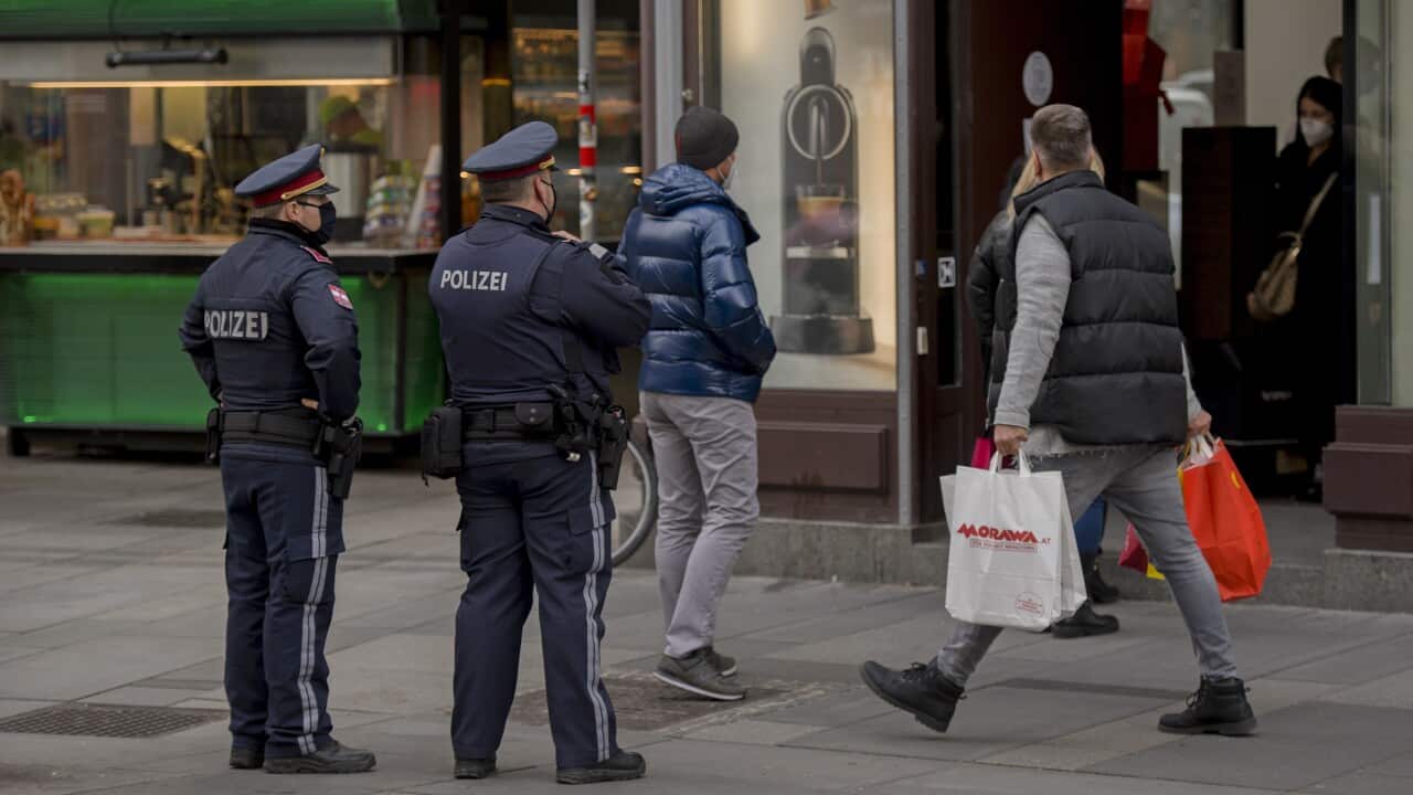 A man carries shopping bags as two police officers patrol streets during lockdown.