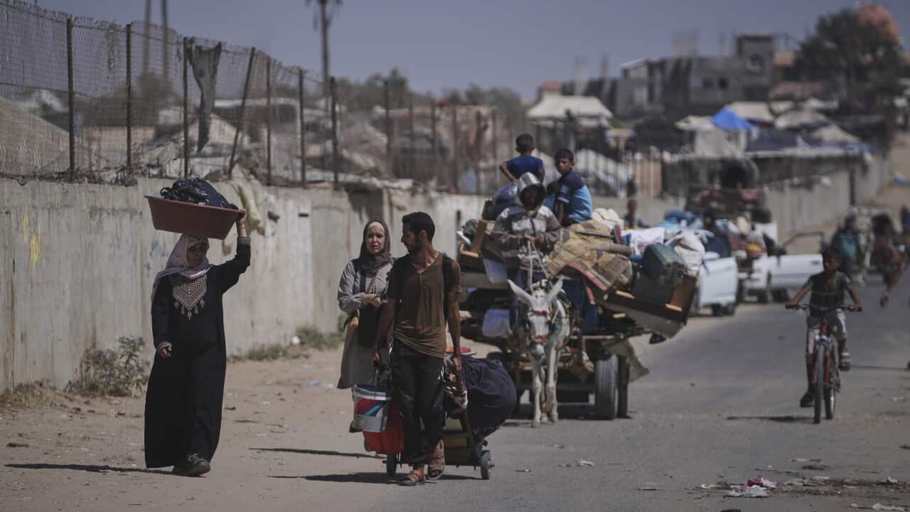 People fleeing a settlement with their belongings, some on foot, on cycles and others on horse-driven carriages.