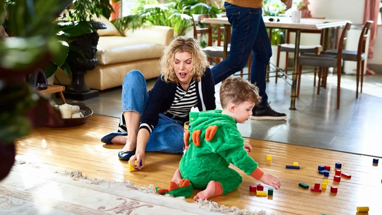 Mother encouraging little boy to play with wooden blocks