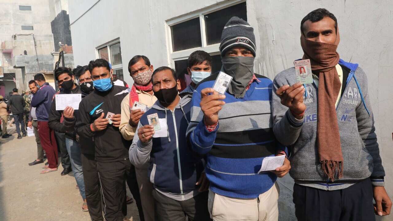 People hold their ID cards as they queue up to cast their votes at a polling station in Yusufpur Chak Saberi village Gautam Budh Nagar in Uttar Pradesh.