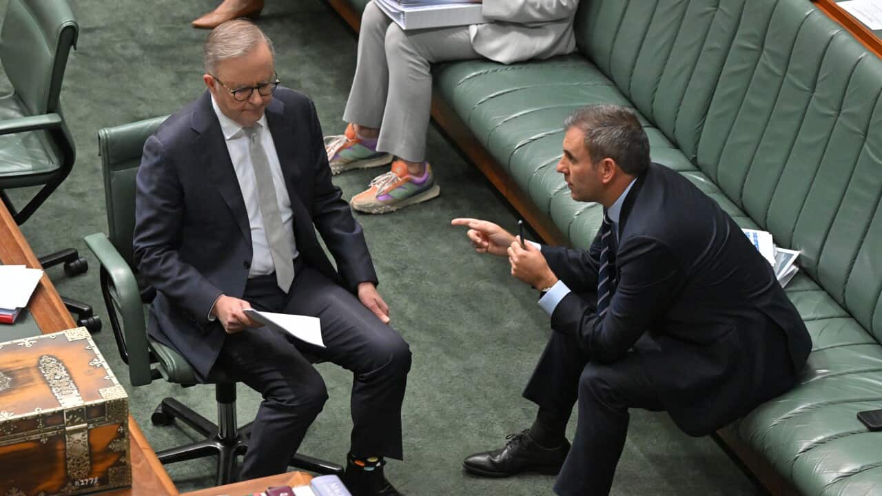Two men in black suits sitting on green seats