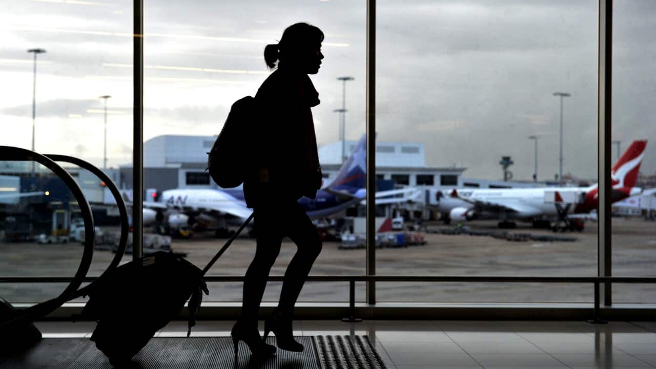 Silhouette of a woman walking through an airport.
