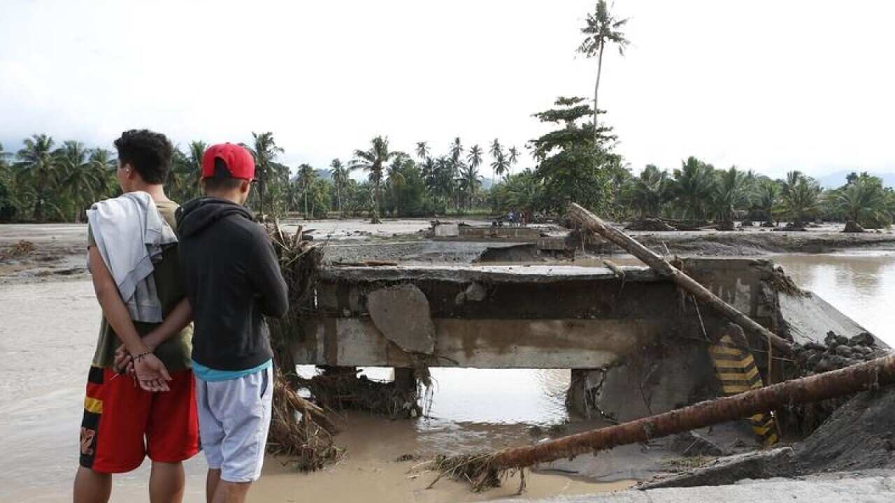 Filipino villagers view a damaged bridge.