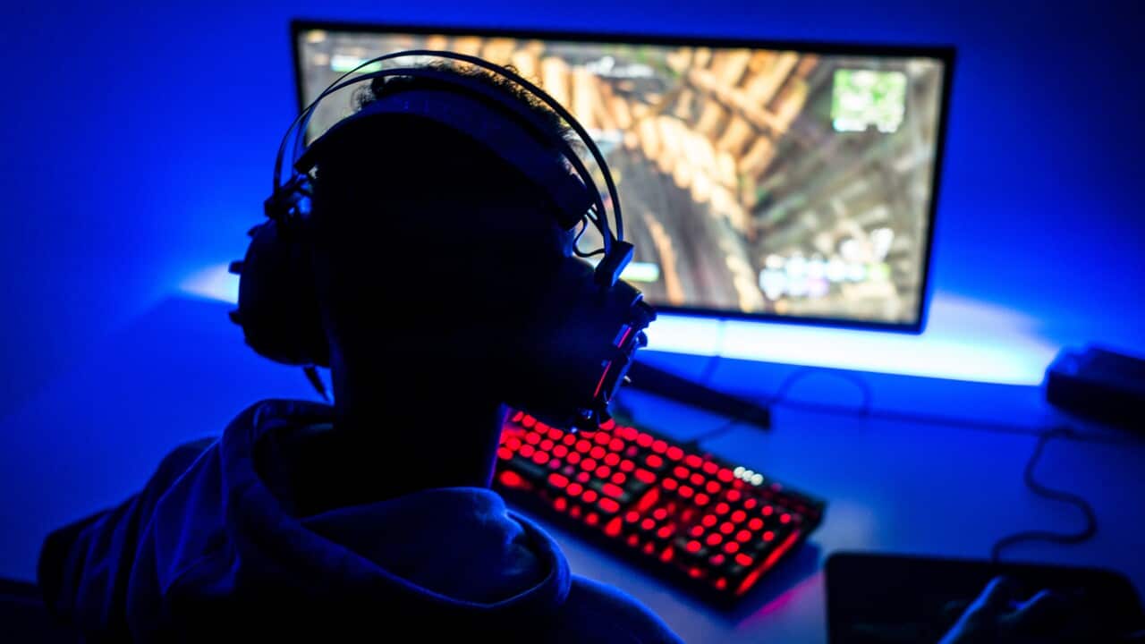 Rear View Of Boy Playing Video Game On Computer In Darkroom