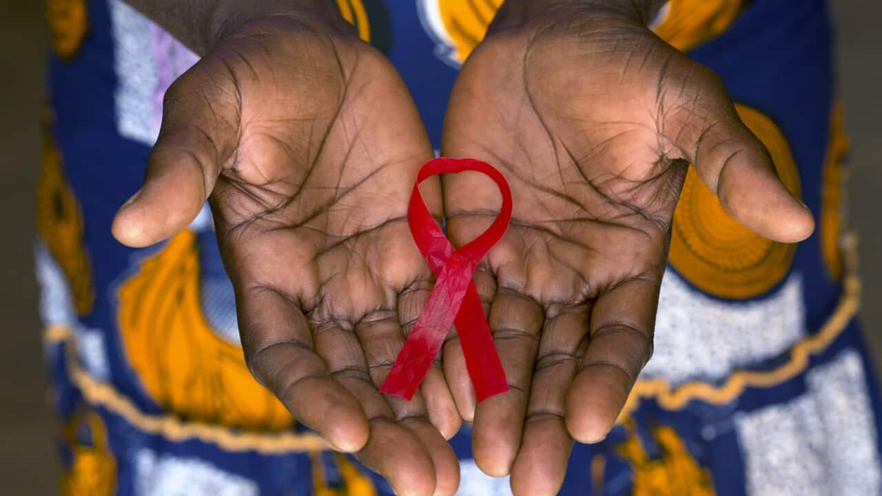 Woman holding red ribbon on her palms in Burkina Faso.