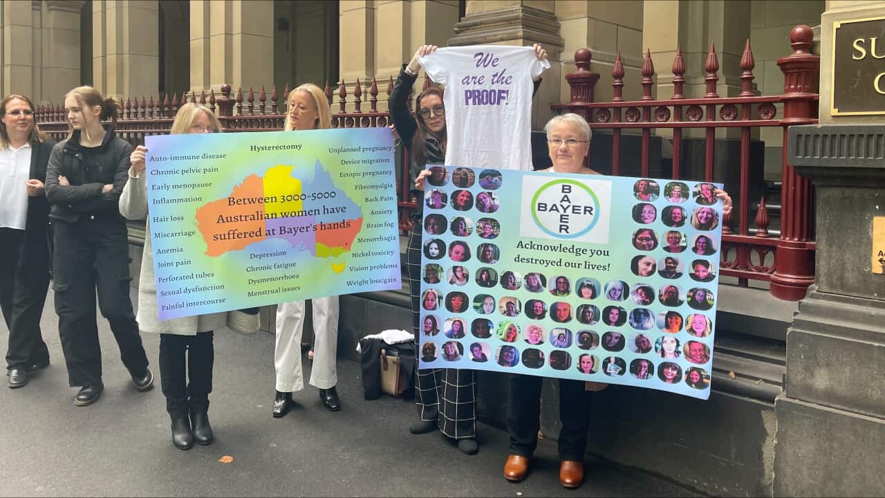 Women standing outside court holding placards.