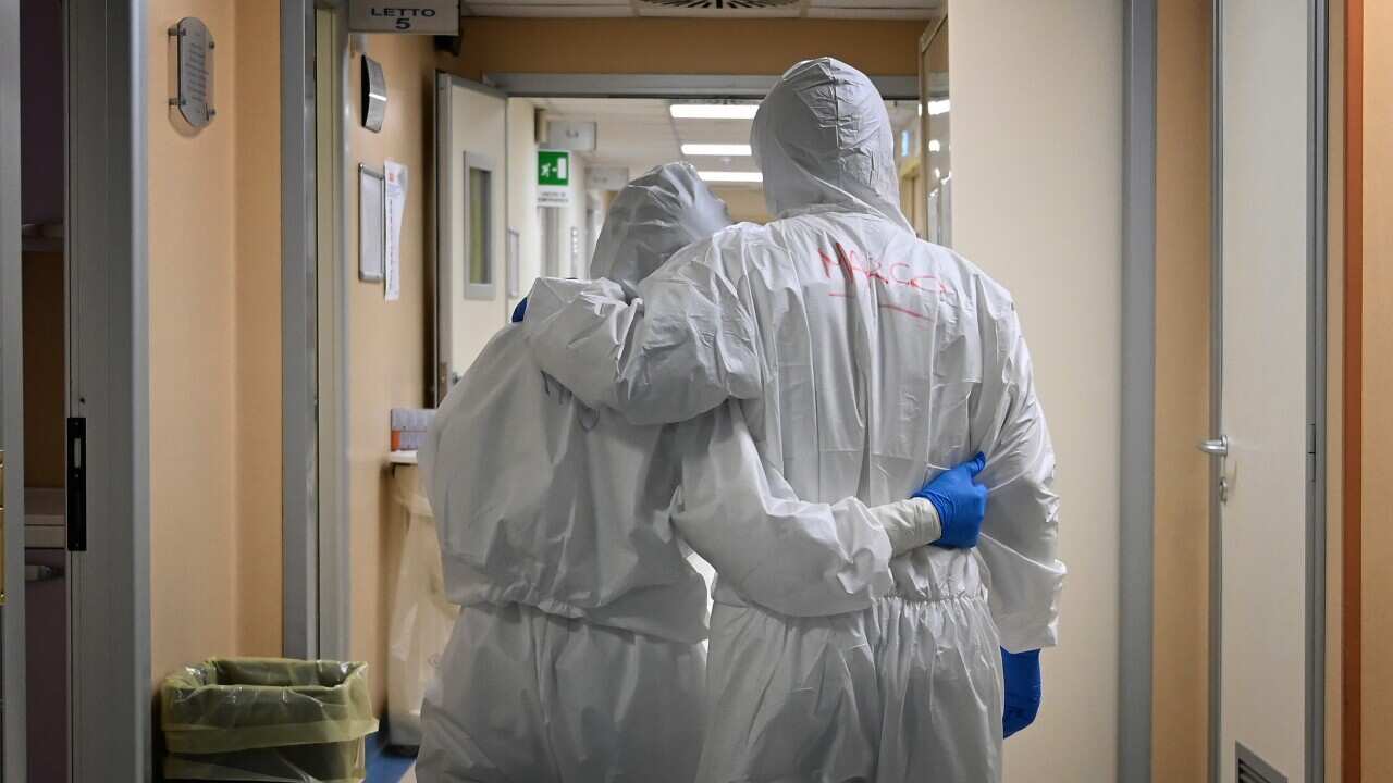 Two health care workers walking down a corridor