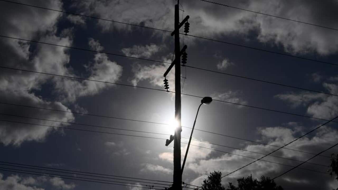 The sun is seen behind a telegraph pole