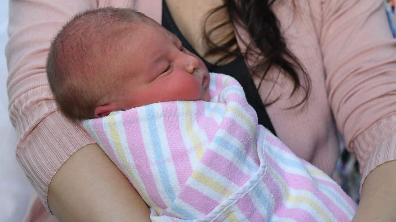 A newborn baby is carried by a woman.