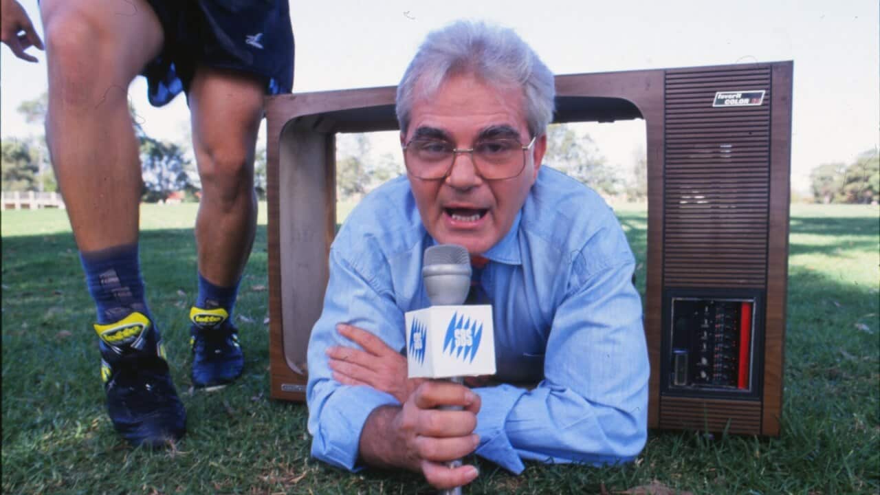 Les Murray with an SBS microphone, lying on grass