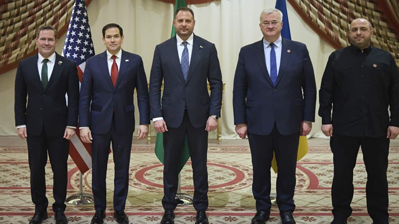 Five men wearing suits posing for a photo