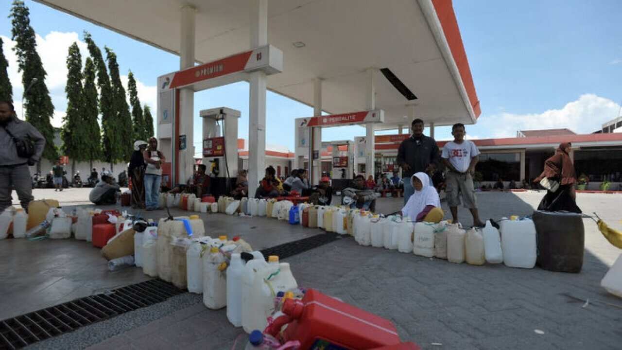Cans are lined up neatly, waiting to be filled at a petrol station in Palu