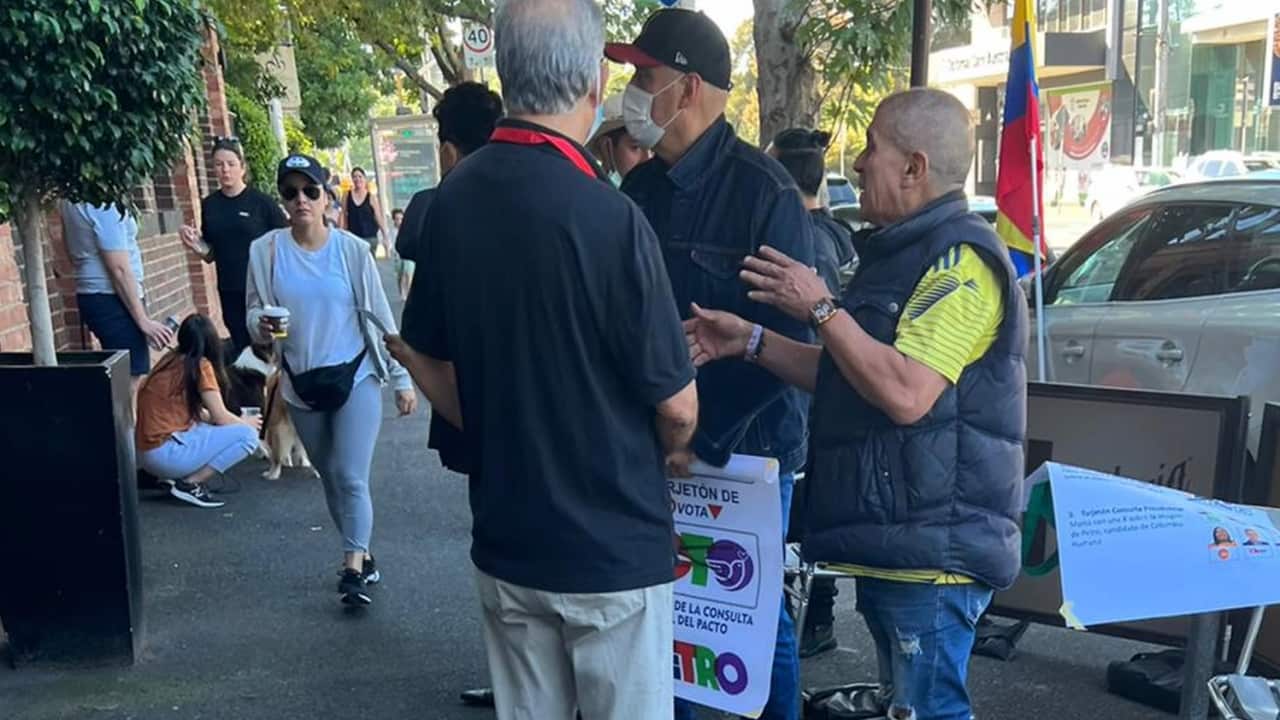 Un grupo de personas exhibe propaganda política ilegal ante un centro de votación en Melbourne