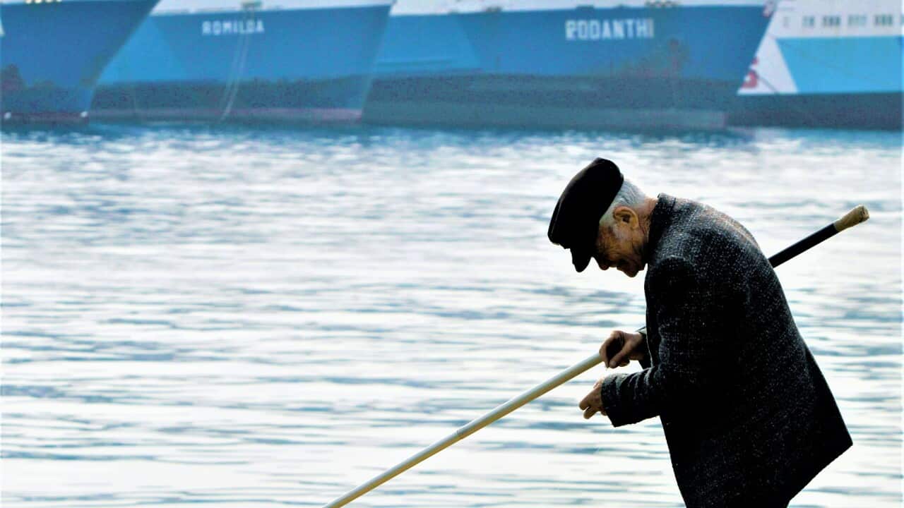 A old man fishes in front of an idle ferry, in the port of Piraeus near Athens, Greece.