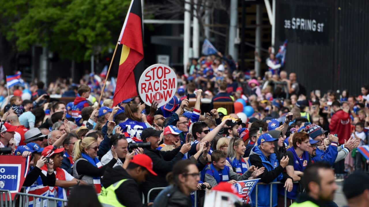 Protesters supporting Adam Goodes walk alongside the AFL Grand Final parade in Melbourne in 2016
