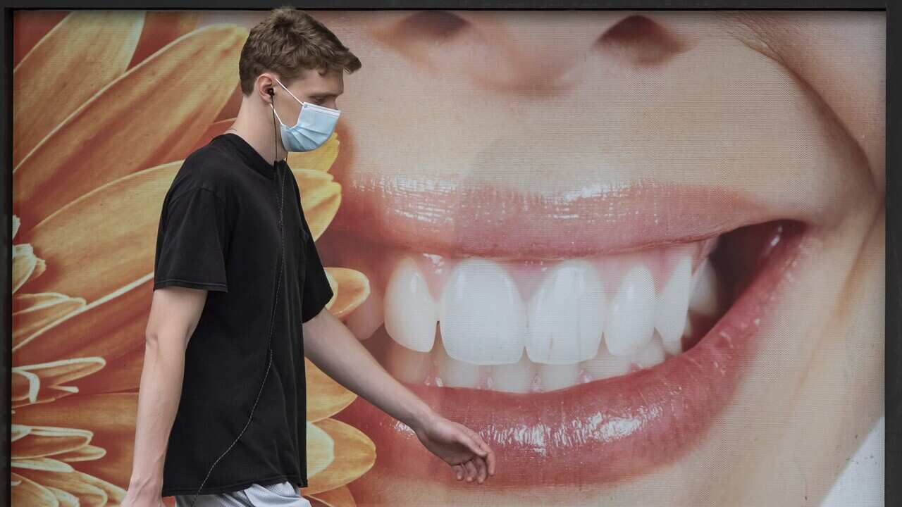 A young man walks past a dental office in Vancouver