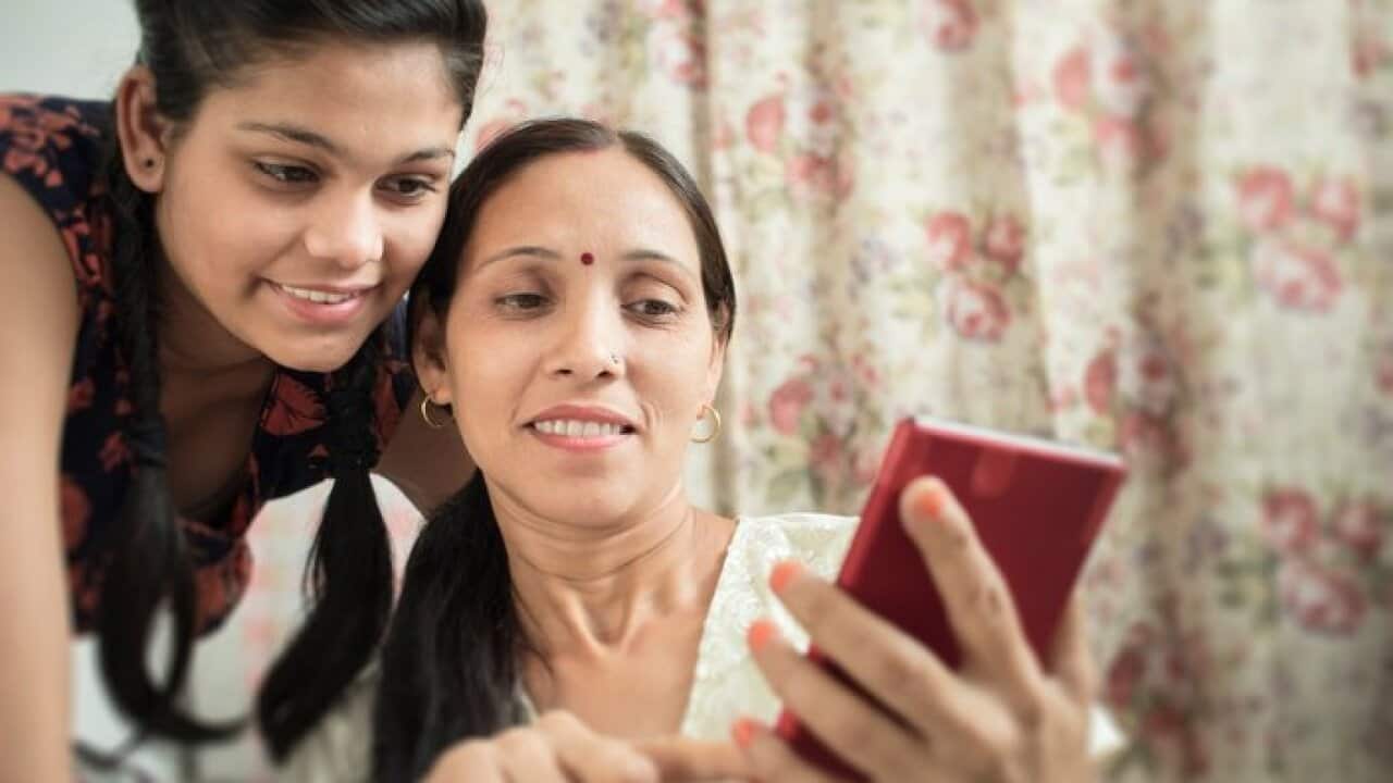 Mother and daughter using phablet together in domestic room.