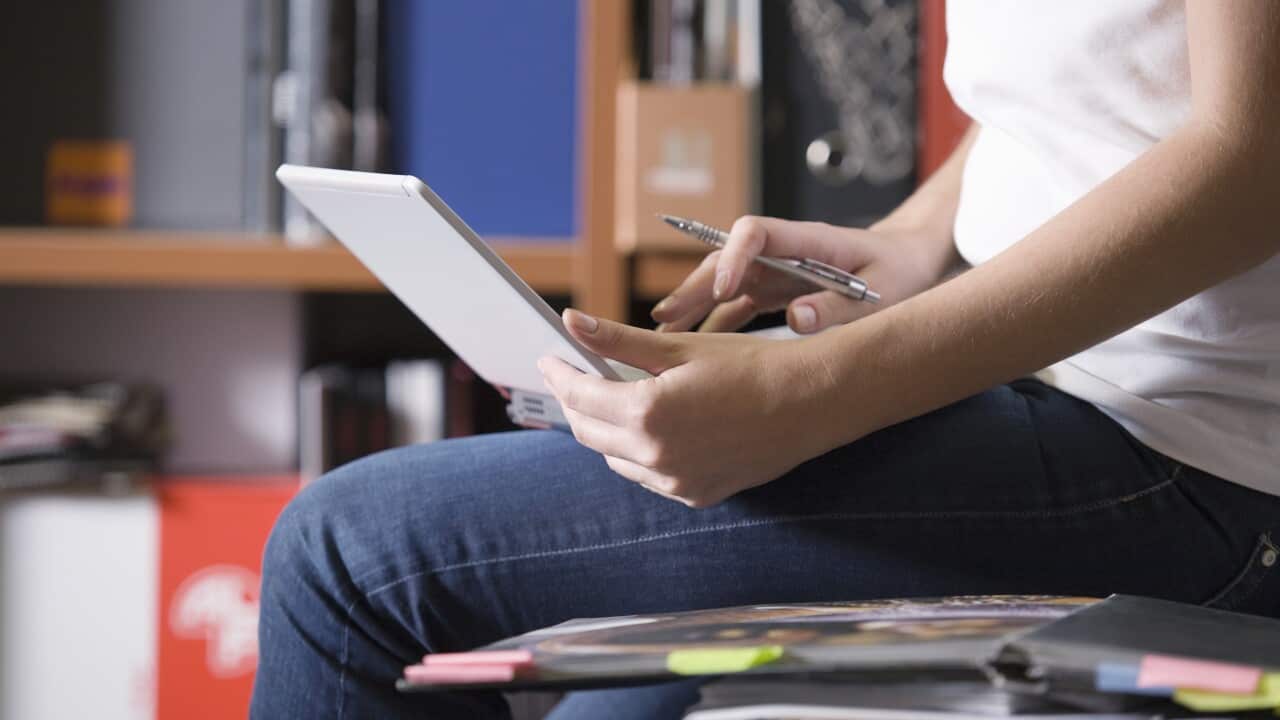 Woman sits working on office desk working on laptop (AAP)