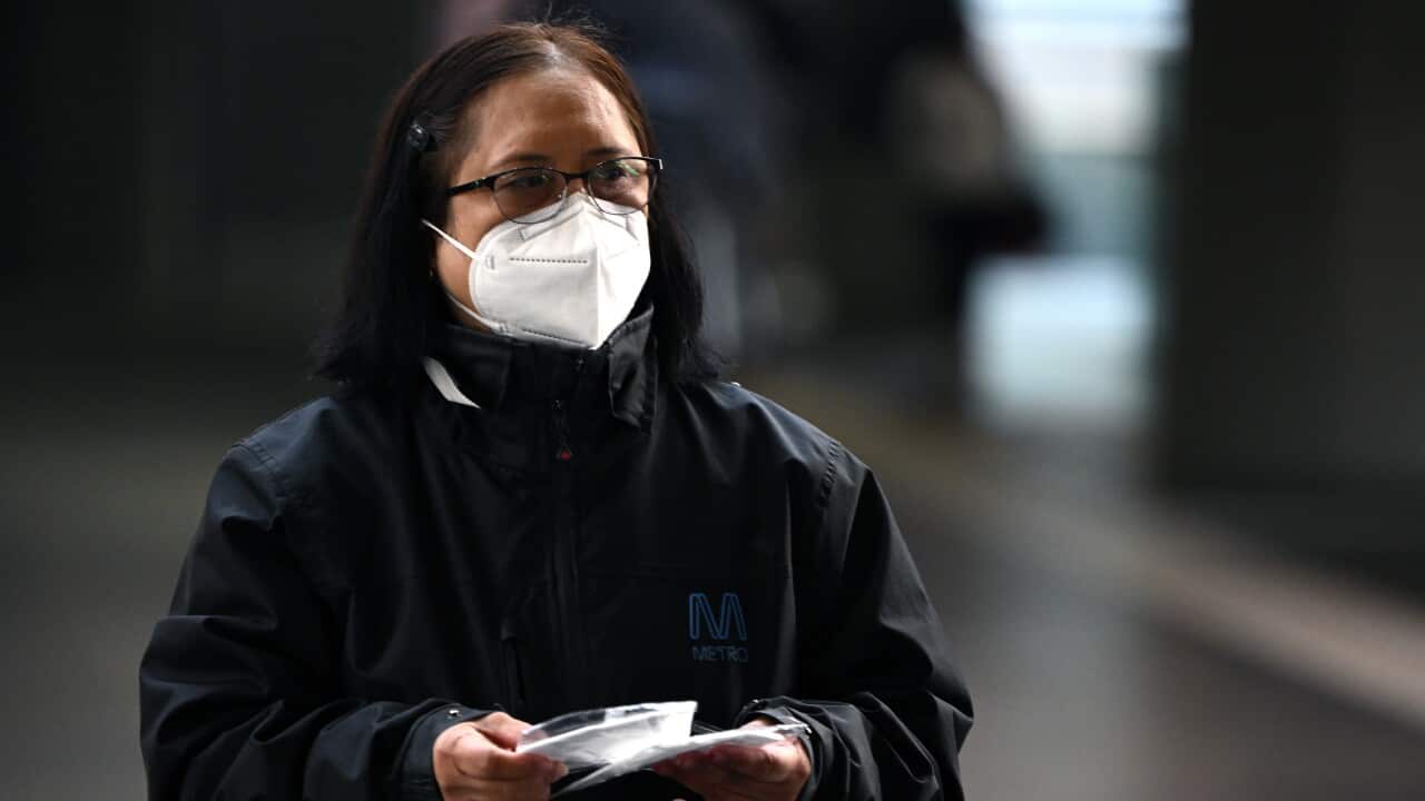 A woman wearing a face mask and a black Metro (Melbourne's train network operator) jacket.