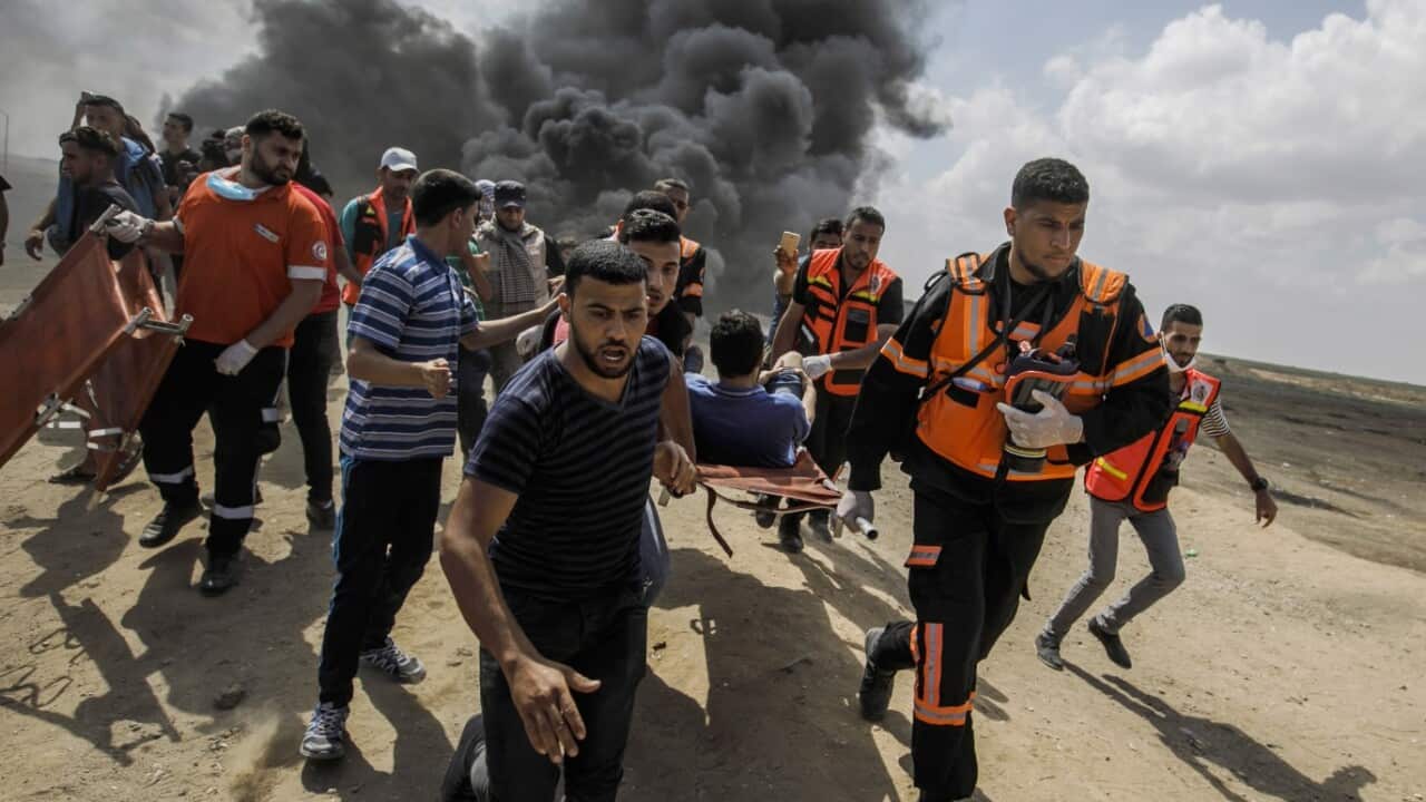 Medical units carry away a wounded Palestinian shot by Israeli forces during a protest on the border fence separating Israel and Gaza on May 14, 2018